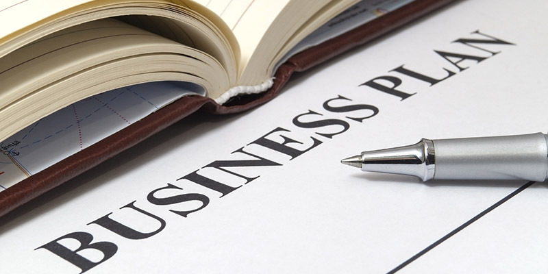 Business plan with a pen and notepad on table close up