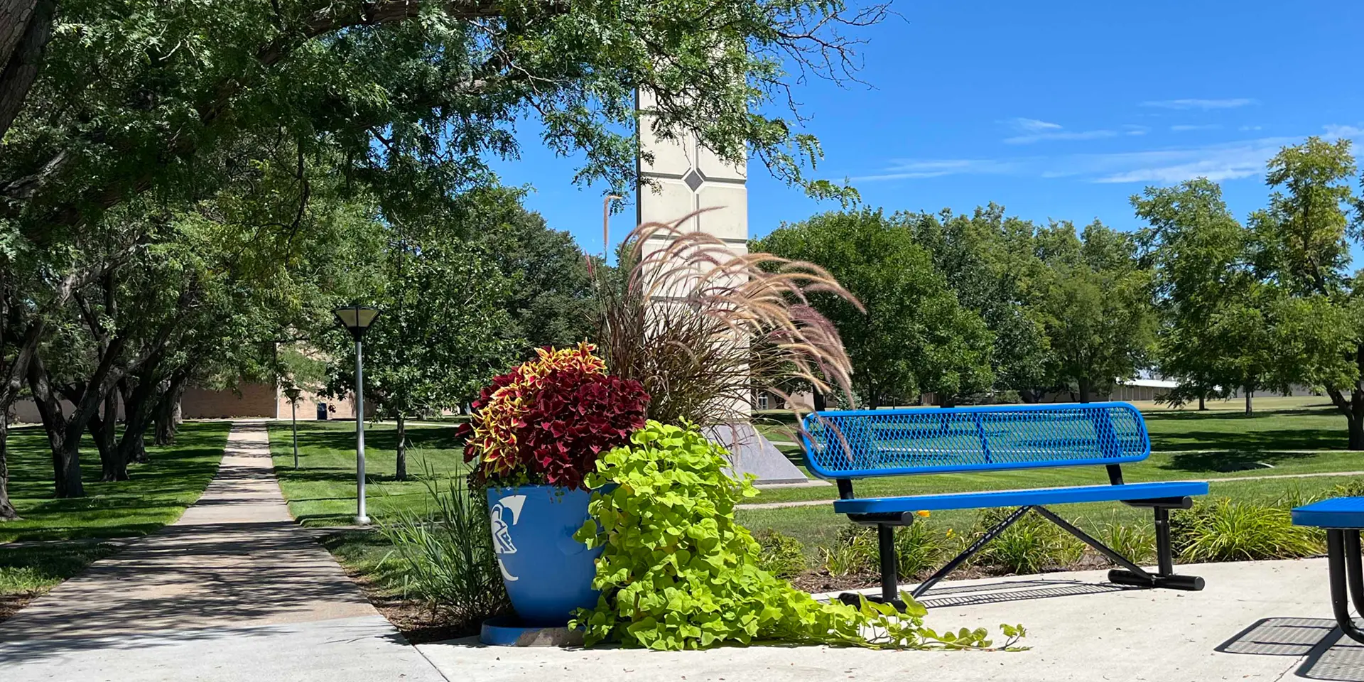 H.F. Davis Library Beatrice Davis Clock Tower with a flower pot branded with the Trojan logo in the foreground